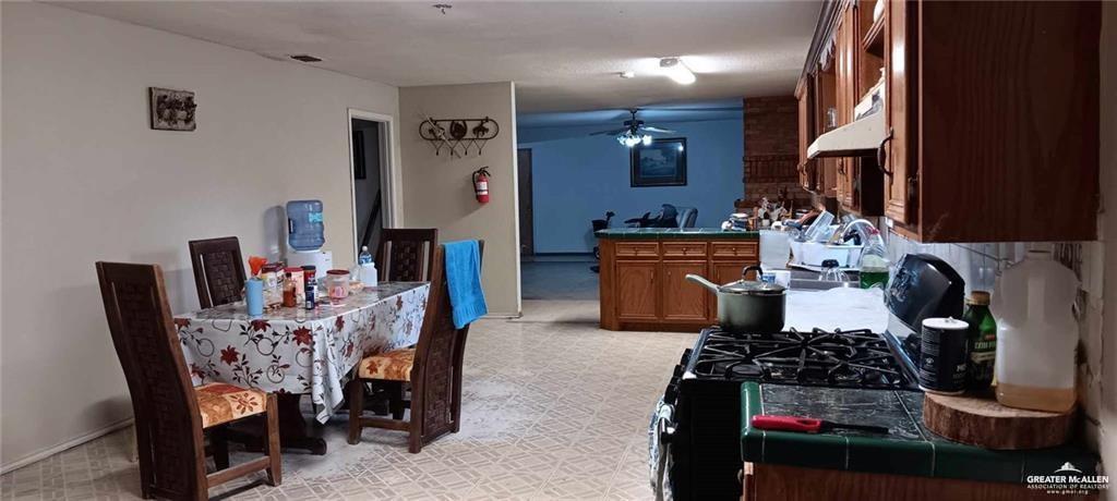 5906 North Brushline Road Mission, TX 78574 - Photo 20 of 29 a kitchen with stainless steel appliances granite countertop a stove a refrigerator a dining table and chairs with wooden floor