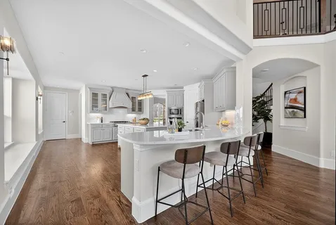 a kitchen with stainless steel appliances a dining table chairs and wooden floor