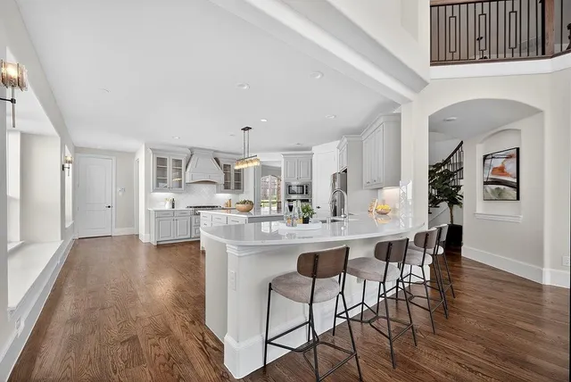 a kitchen with stainless steel appliances a dining table chairs and wooden floor