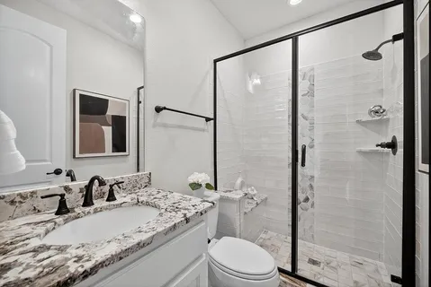 a bathroom with a granite countertop sink toilet mirror and shower