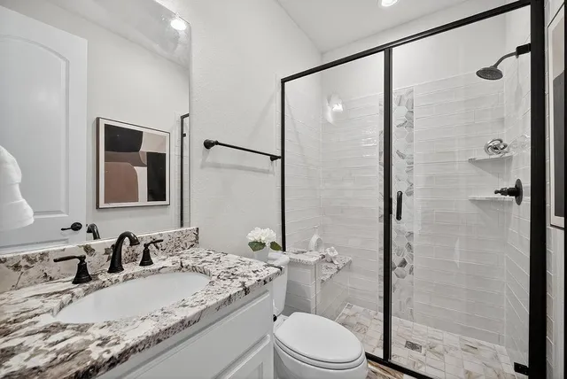 a bathroom with a granite countertop sink toilet mirror and shower