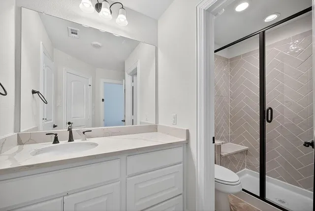 a bathroom with a double vanity sink toilet and shower
