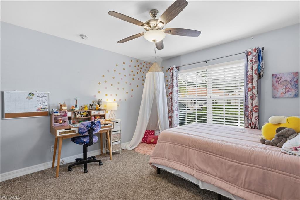 1770 Ribbon Fan Lane Naples, FL 34119 - Photo 22 of 37 a bedroom with a bed a desk and a chandelier