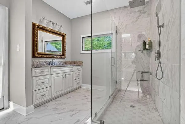a bathroom with a granite countertop sink mirror and shower