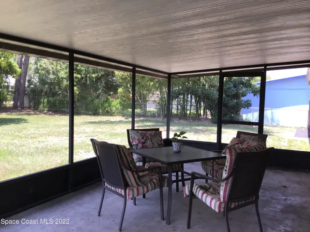 a view of a dining room with furniture and large windows