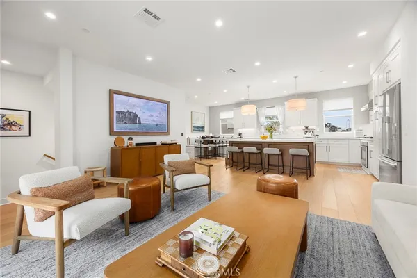 a living room with stainless steel appliances kitchen island granite countertop a couch and white cabinets