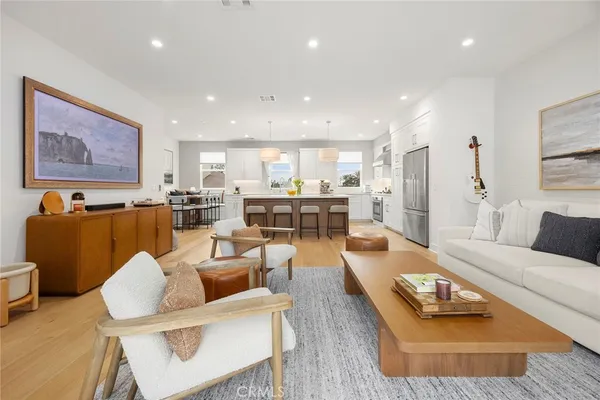a living room with furniture kitchen view and a large window
