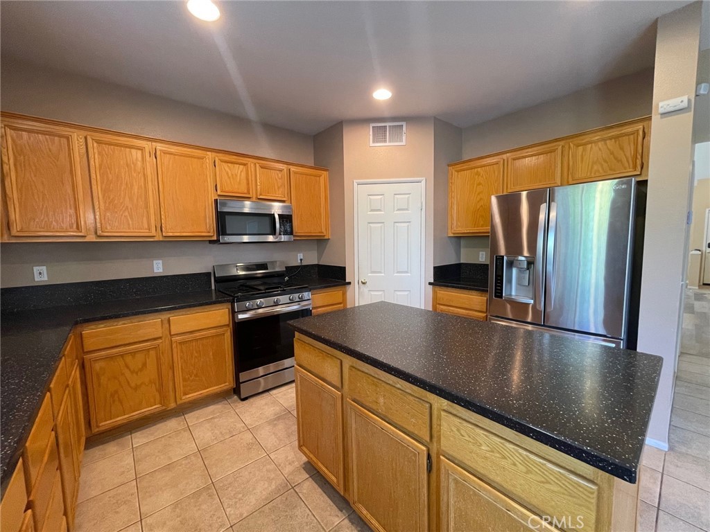 1434 Haddington Drive Riverside, CA 92507 - Photo 13 of 40 a kitchen with granite countertop a refrigerator stove top oven microwave and cabinets