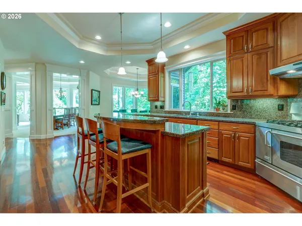 a kitchen with stainless steel appliances granite countertop wooden cabinets a dining table and chairs