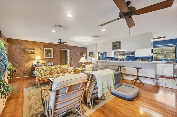 a living room with stainless steel appliances furniture and a kitchen view