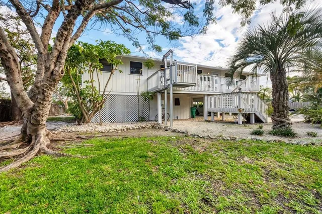 a view of a white house with a large tree and a yard in front of it