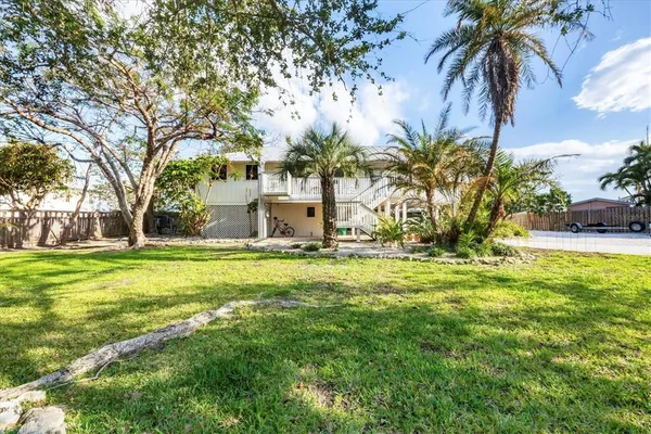 a palm tree sitting in front of a house with a garden
