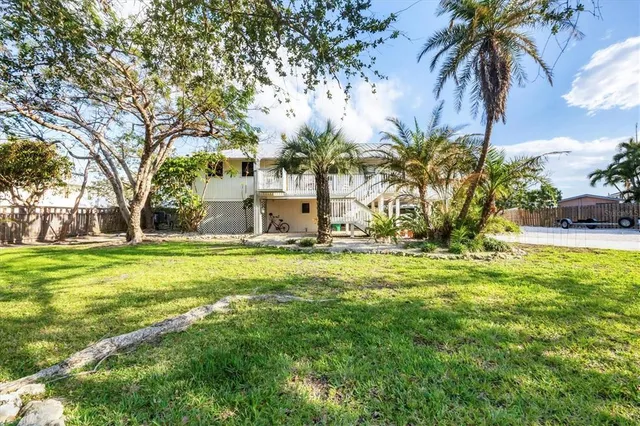 a palm tree sitting in front of a house with a garden