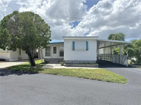 a view of yellow house with a yard and large tree