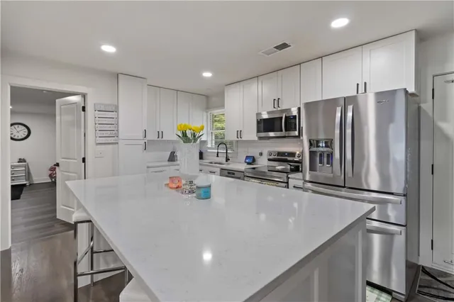 a large kitchen with stainless steel appliances a refrigerator sink stove microwave and cabinets