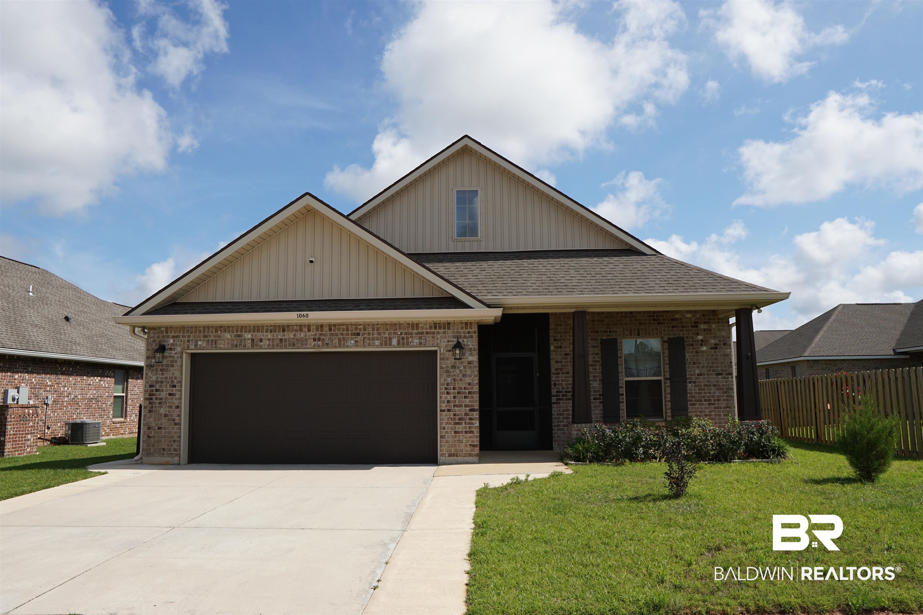 1060 Chloe Street Foley, AL 36535 - Photo 27 of 28 Brick facade home with a dark garage door, covered entry, and traditional shutters