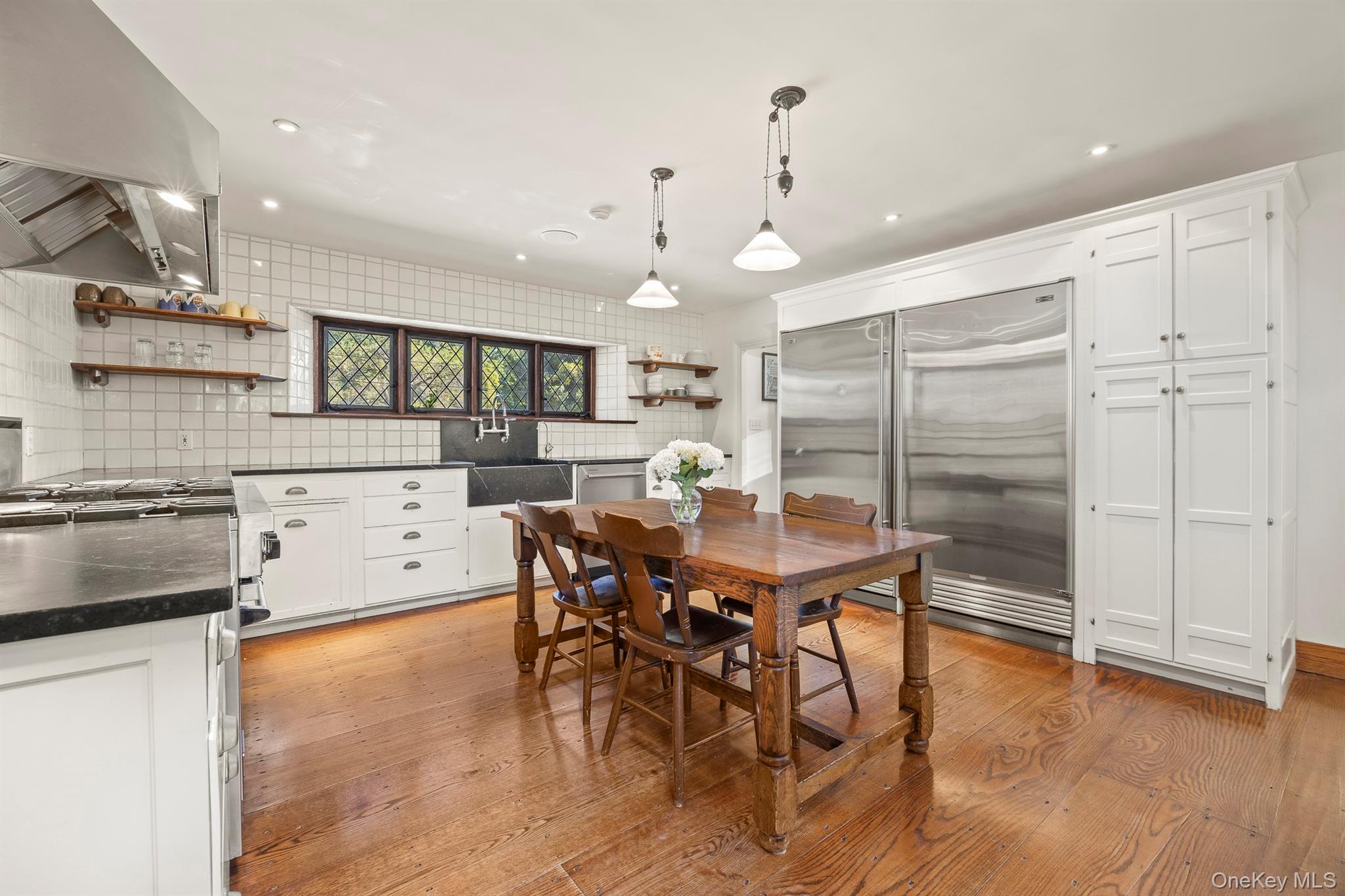 99 Quaker Bridge Road Croton-on-Hudson, NY 10520 - Photo 12 of 50 a kitchen with stainless steel appliances kitchen island granite countertop a stove a refrigerator and a dining table with wooden floor
