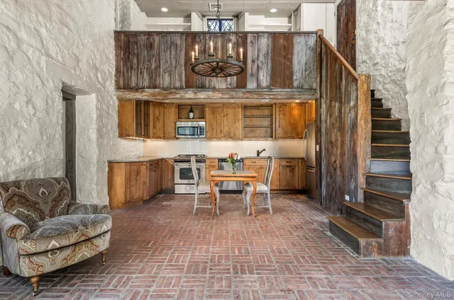 a living room with stainless steel appliances furniture a rug and a kitchen view