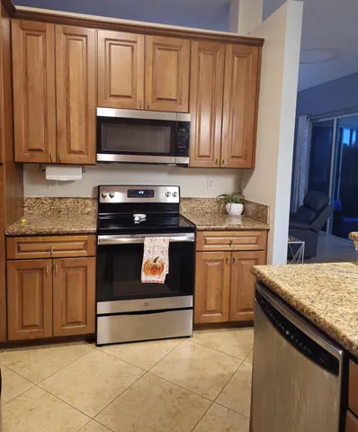 a kitchen with granite countertop a stove top oven microwave and cabinets