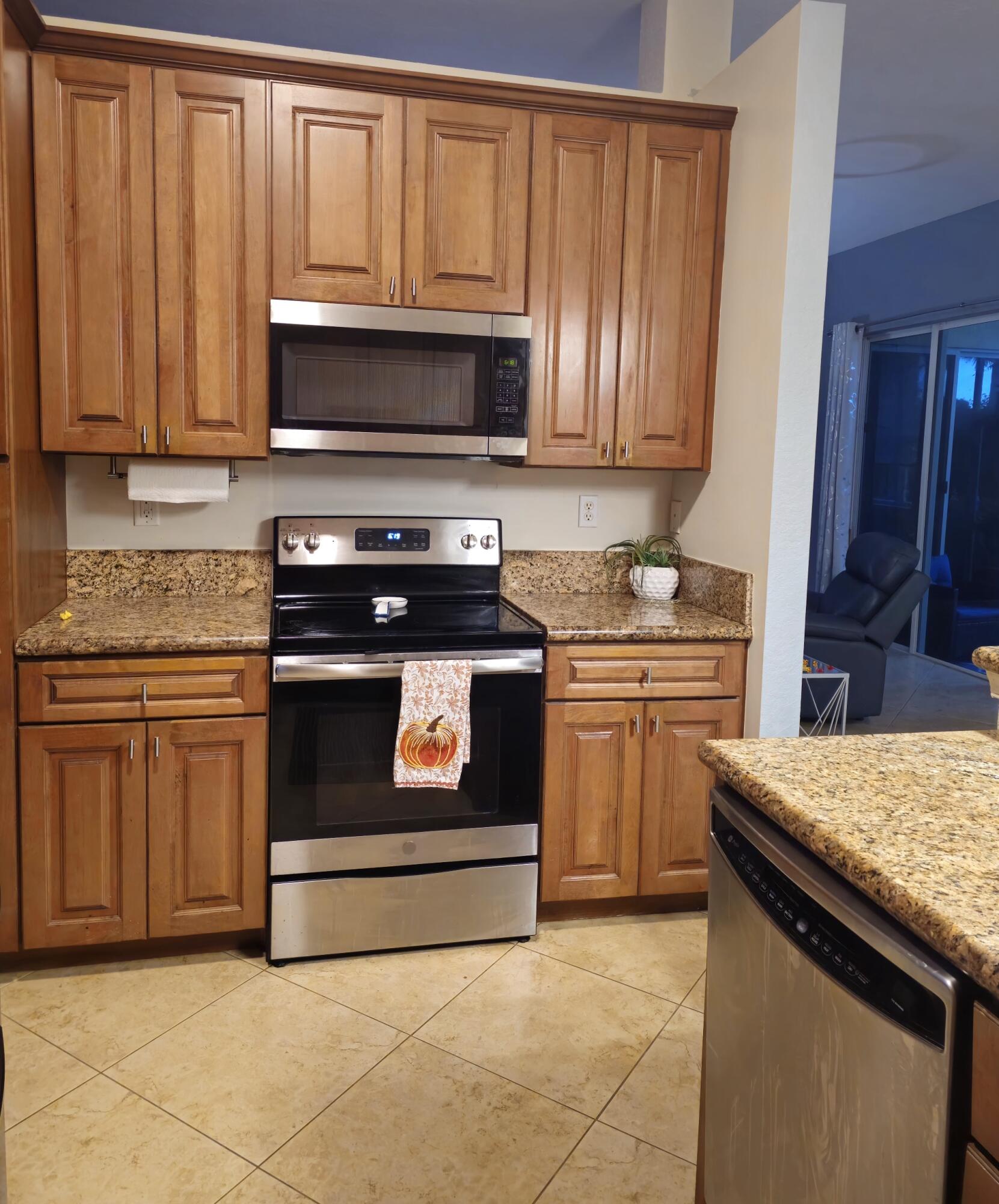 9770 Bowline Drive, Unit 102 West Palm Beach, FL 33411 - Photo 3 of 27 a kitchen with granite countertop a stove top oven microwave and cabinets