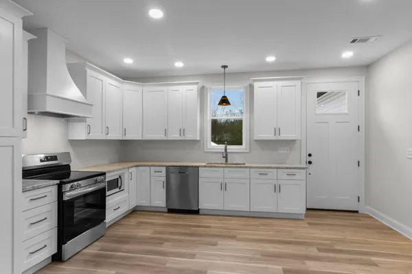 a large kitchen with stainless steel appliances granite countertop a stove and a sink