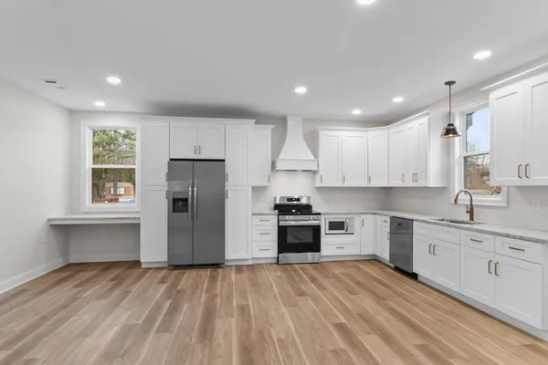 a kitchen with granite countertop a refrigerator stove top oven and sink