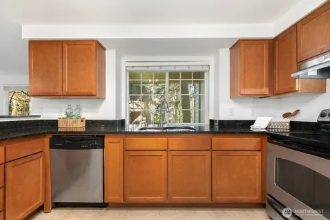 a kitchen with granite countertop cabinets stainless steel appliances a sink and a window