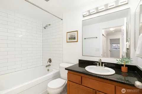 a bathroom with a granite countertop sink toilet a mirror and bathtub