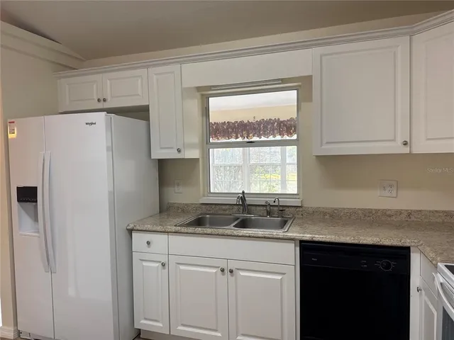 a kitchen with granite countertop a refrigerator sink and cabinets