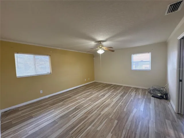 a view of empty room with wooden floor and fan