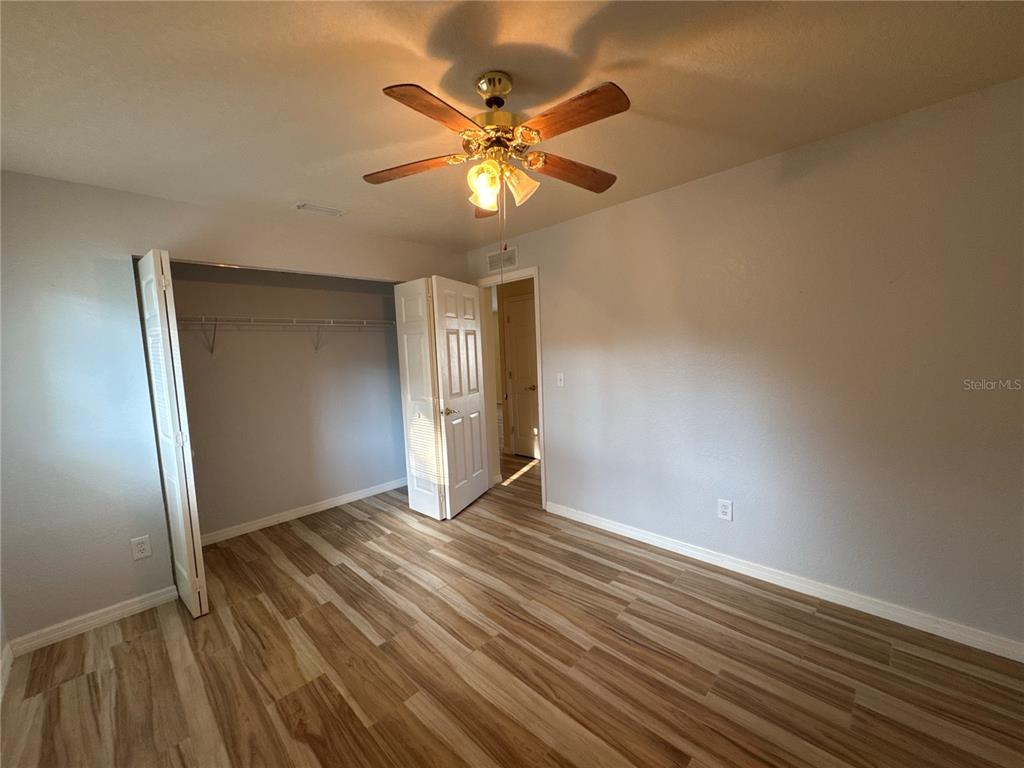 5440 Southwest 100th Loop Ocala, FL 34476 - Photo 15 of 37 a view of an empty room with wooden floor and a ceiling fan