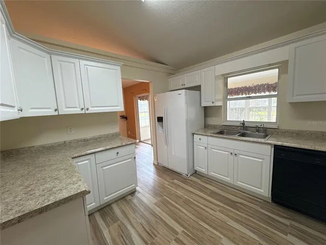 a kitchen with granite countertop white cabinets and white appliances