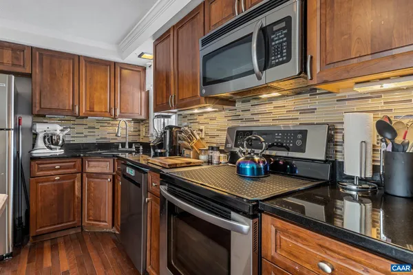 a kitchen with stainless steel appliances granite countertop a stove a sink and a microwave
