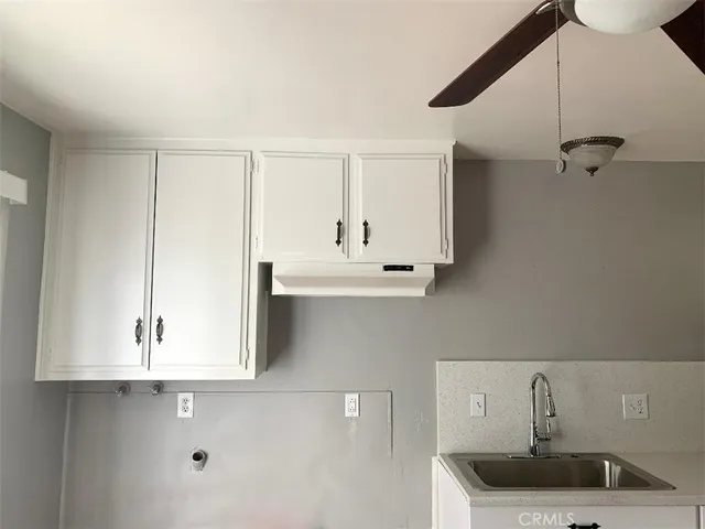 a kitchen with white cabinets and sink