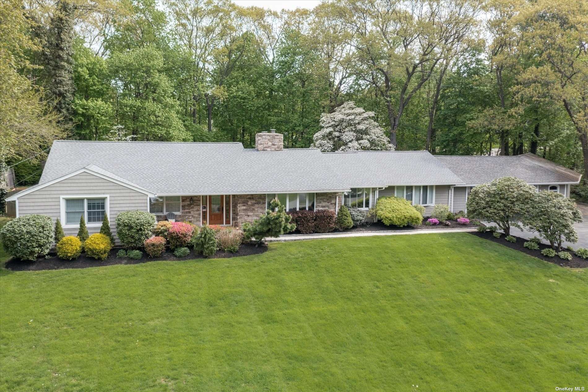 a aerial view of a house next to a big yard and large trees