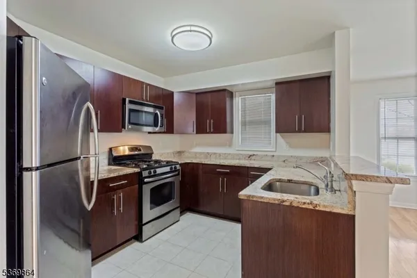 a kitchen with stainless steel appliances granite countertop a refrigerator stove a sink dishwasher and microwave