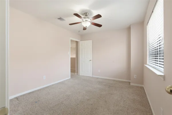 a view of an empty room with window and ceiling fan