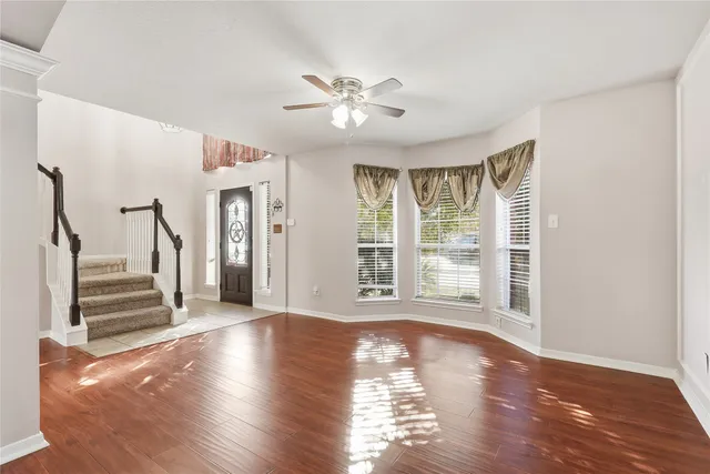 a view of a livingroom with wooden floor and a ceiling fan