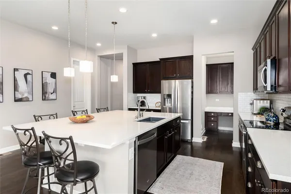 a kitchen with stainless steel appliances kitchen island granite countertop a stove a sink a refrigerator and chairs
