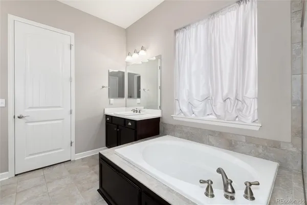 a spacious bathroom with a tub sink and mirror