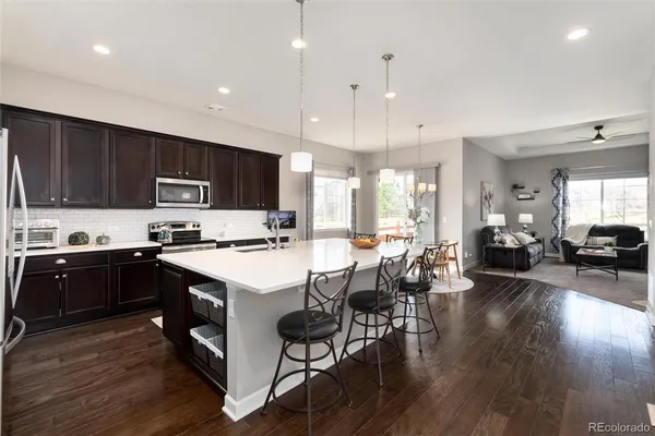 a kitchen with stainless steel appliances granite countertop a stove top oven a sink dishwasher a dining table and chairs with wooden floor