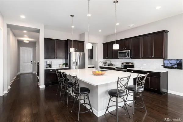 a kitchen with stainless steel appliances kitchen island granite countertop a stove a refrigerator a kitchen island a sink and a refrigerator with wooden floor