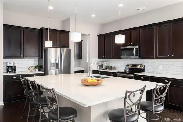a kitchen with granite countertop a table chairs stove and refrigerator with wooden floor