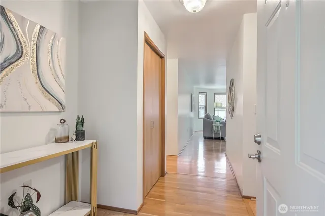 a view of a hallway with wooden floor and a bathroom