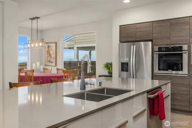 a kitchen with stainless steel appliances a sink a refrigerator a stove and white cabinets