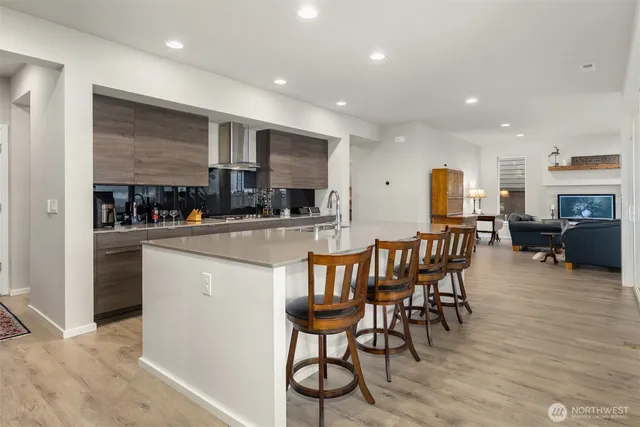 a kitchen with stainless steel appliances kitchen island granite countertop a dining table chairs and a refrigerator