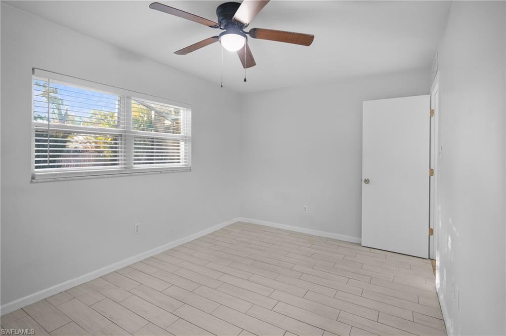 3581 Corana Way Naples, FL 34105 - Photo 14 of 26 a view of an empty room with wooden floor and a window