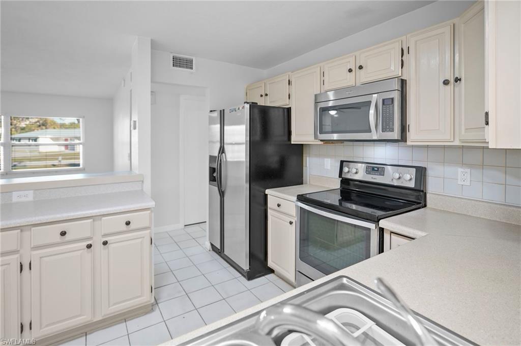 3581 Corana Way Naples, FL 34105 - Photo 16 of 26 a kitchen with stainless steel appliances granite countertop a stove a refrigerator and a cabinets