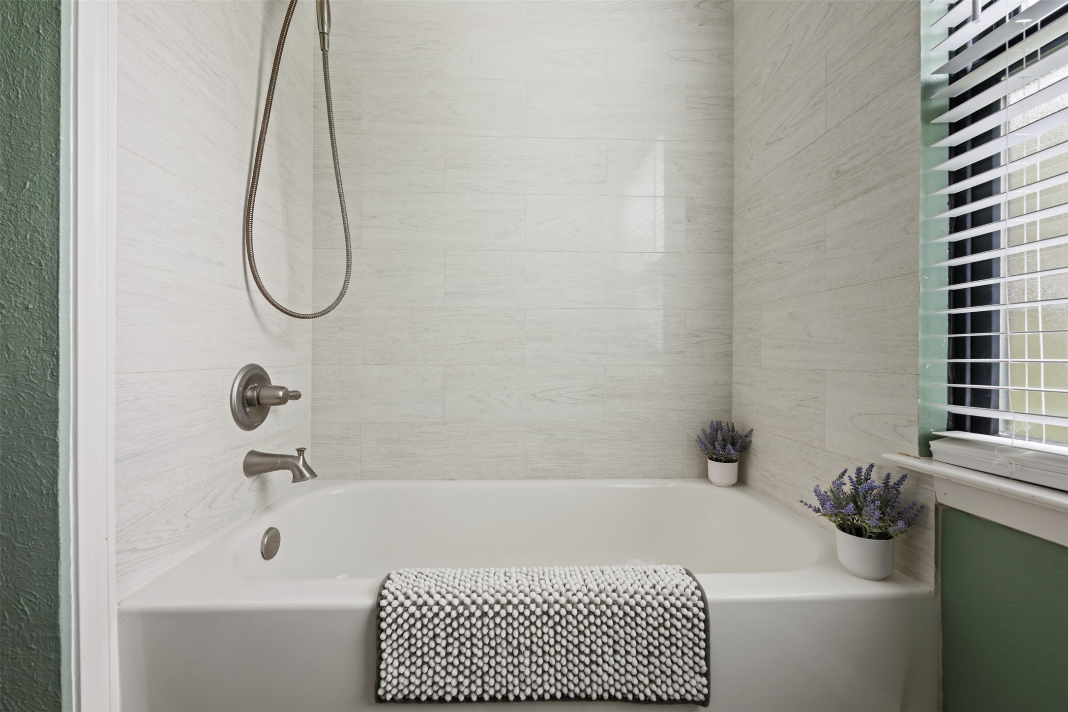 1600 Pin Oak Lane Round Rock, TX 78681 - Photo 31 of 40 Bathtub with light-toned tiled surround, brushed nickel fixtures, and a window with horizontal blinds