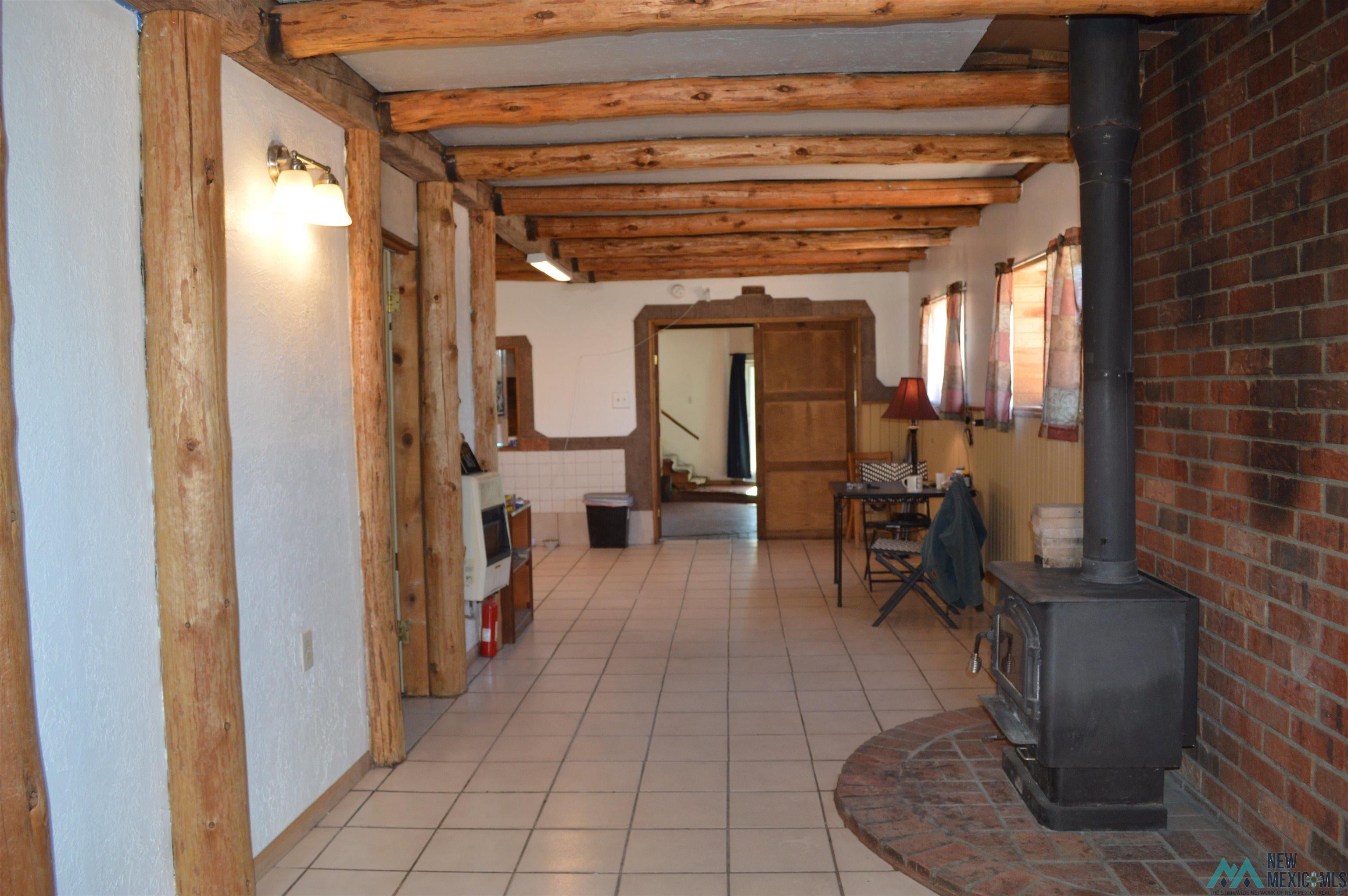 6 Sunny Dale Road Bluewater, NM 87005 - Photo 33 of 42 Spacious interior featuring exposed log beams, white textured walls, and light-toned square floor tiles